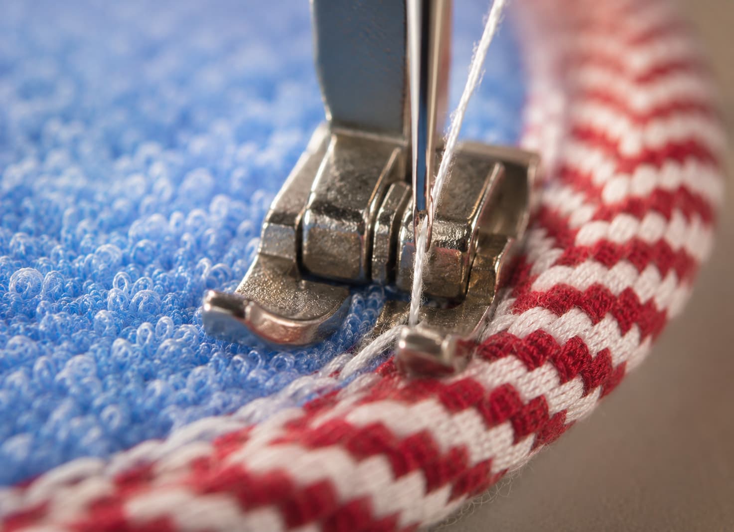 Close-up of a loofah piece being machine-stitched to cotton towel